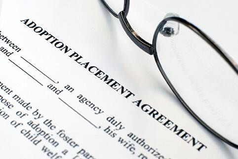 Paper with adoption  Placement agreement text and a pair of glasses laying on the paper