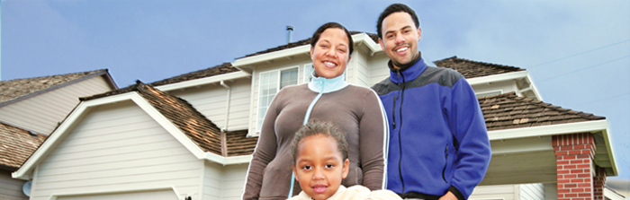 Photograph of a man, woman, and child standing in front of a house