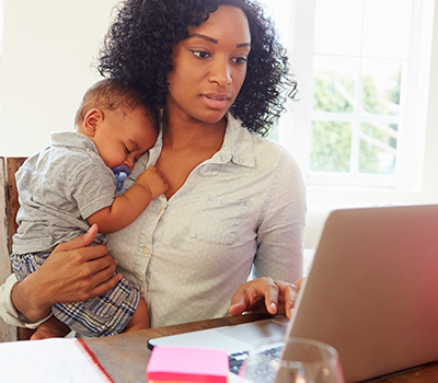  image of a woman using a computer while she holds her baby