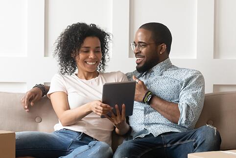 picture of a man and a woman sitting on a couch looking at a tablet