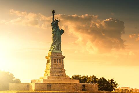 Statue of Liberty with sun setting and clouds in the sky