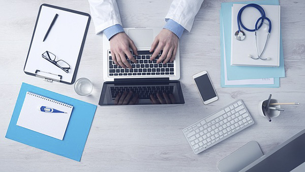 An image of a physician typing on a laptop.