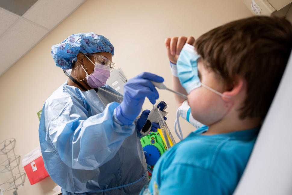 A nurse at St. Jude Children's Research Hospital, checks a young boy's temperature prior to testing him for COVID-19.