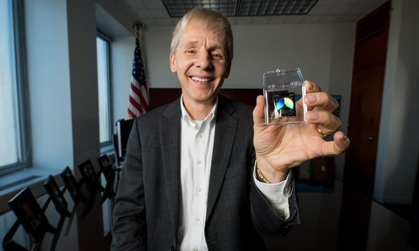 Man holding a NIST on a Chip device