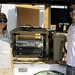 Sonja Behnke with a gray shirt and brown hat with David Hemsing wearing a white polo shirt standing next to the RF sensor 