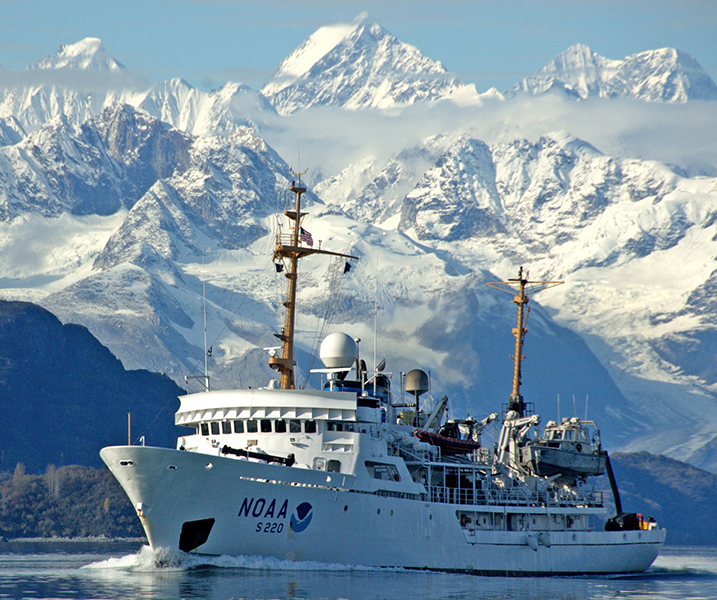 NOAA Ship Fairweather sailing in Alaska with mountains in the backdrop.