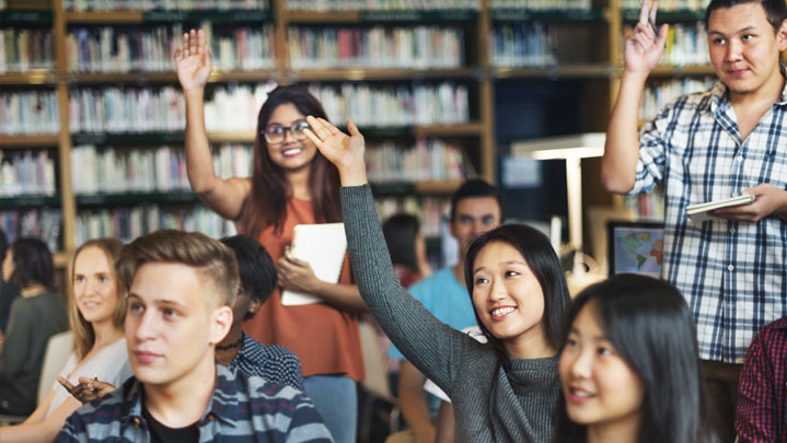 students raising their hands in class