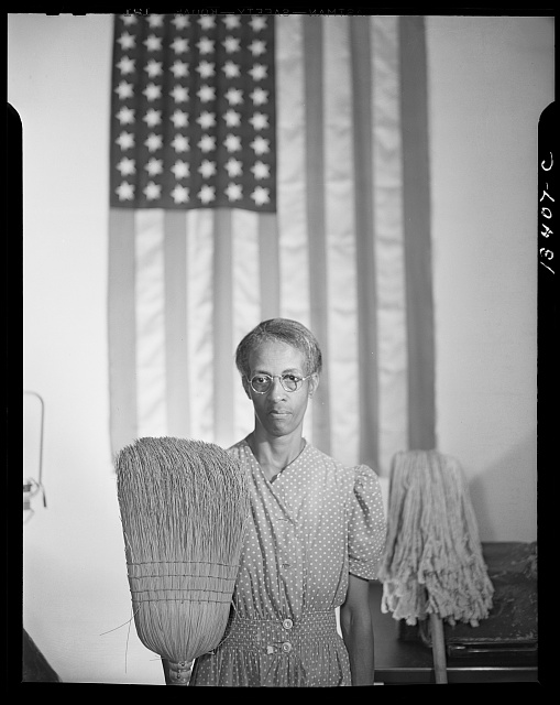 Photograph by Gordon Parks of Ella Watson with mop and broom in front of American flag
