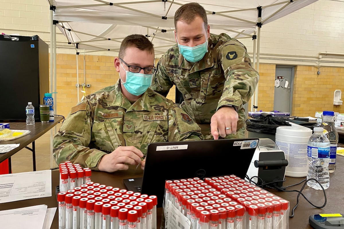 Two service members look at a computer monitor.