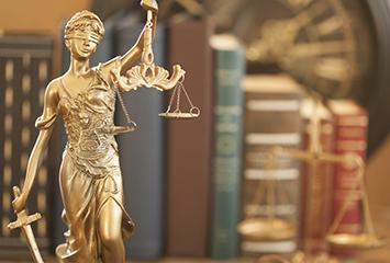 A statue of lady justice profiled in front of law books.