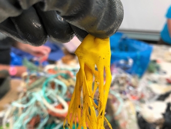 A black, gloved hand holds up a yellow shredded balloon that resembles a jellyfish.