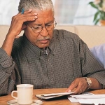 Older man filling out legal and financial paperwork for people with Alzheimer's disease