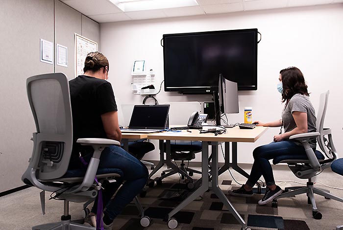 Two women sitting in front of desk top computers