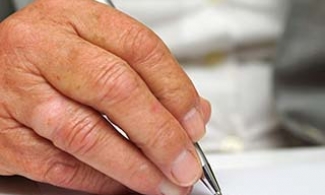 Older person's hand writing down health care directives