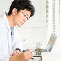 Man in lab coat sitting at desk with computer 