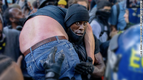 LONDON, UNITED KINGDOM - JUNE 13: A group of men including Patrick Hutchinson (carrying the man) help an injured man away after he was allegedly attacked by some of the crowd of protesters as police try to intervene on the Southbank near Waterloo station on June 13, 2020 in London, United Kingdom. Following a social media post by the far-right activist known as Tommy Robinson, members of far-right linked groups have gathered around statues in London. Several statues in the UK have been targeted by Black Lives Matter protesters for their links to racism and the slave trade. (Photo by Luke Dray/Getty Images)