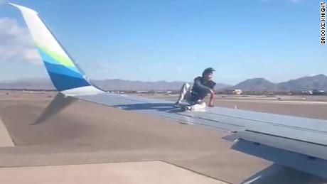 A man sits on the wing of an Alaska Airlines plane minutes before takeoff at McCarran International Airport in Las Vegas, Nevada.