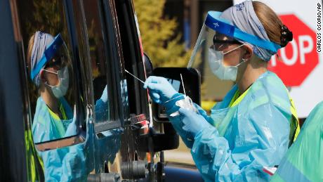 Healthcare workers test a person at a COVID-19 drive-thru testing site at Henry Ford West Bloomfield Hospital, Wednesday, March 25, 2020, in West Bloomfield, Mich. (AP Photo/Carlos Osorio)