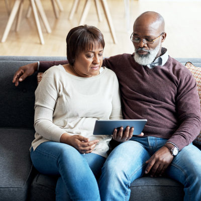 An older couple watching a video together on a tablet device.