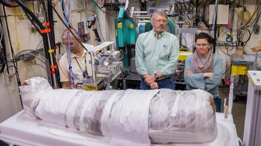 Stuart Stock, center, of Northwestern University, talks with Rachel Sabino, right, of the Art Institute of Chicago in 2017 while Argonne scientist Ali Mashayekhi, left, makes adjustments to the apparatus holding a 1,900-year-old Egyptian mummy. (Image by Mark Lopez / Argonne National Laboratory.)