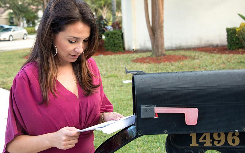 una mujer leyendo el correo del buzón