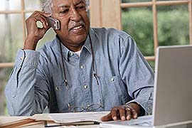 Man looking at computer while talking on the phone