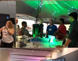 A handful of people under a tent with a green star projector.