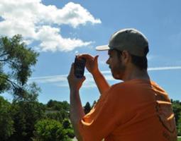 A man uses a smartphone to do cloud observations