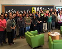 Group photo in front of a banner that says "Welcome to Bond Wilson".