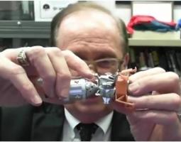 Jerry Woodfill holds an Apollo 11 model in front of a webcam.