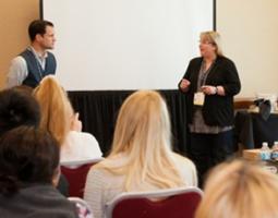 A man and woman speak in front of an audience.