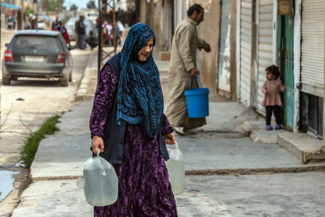 A mother carries water which UNICEF has been trucking daily to reach families in makeshift camps in the Syrian Arab Republic.