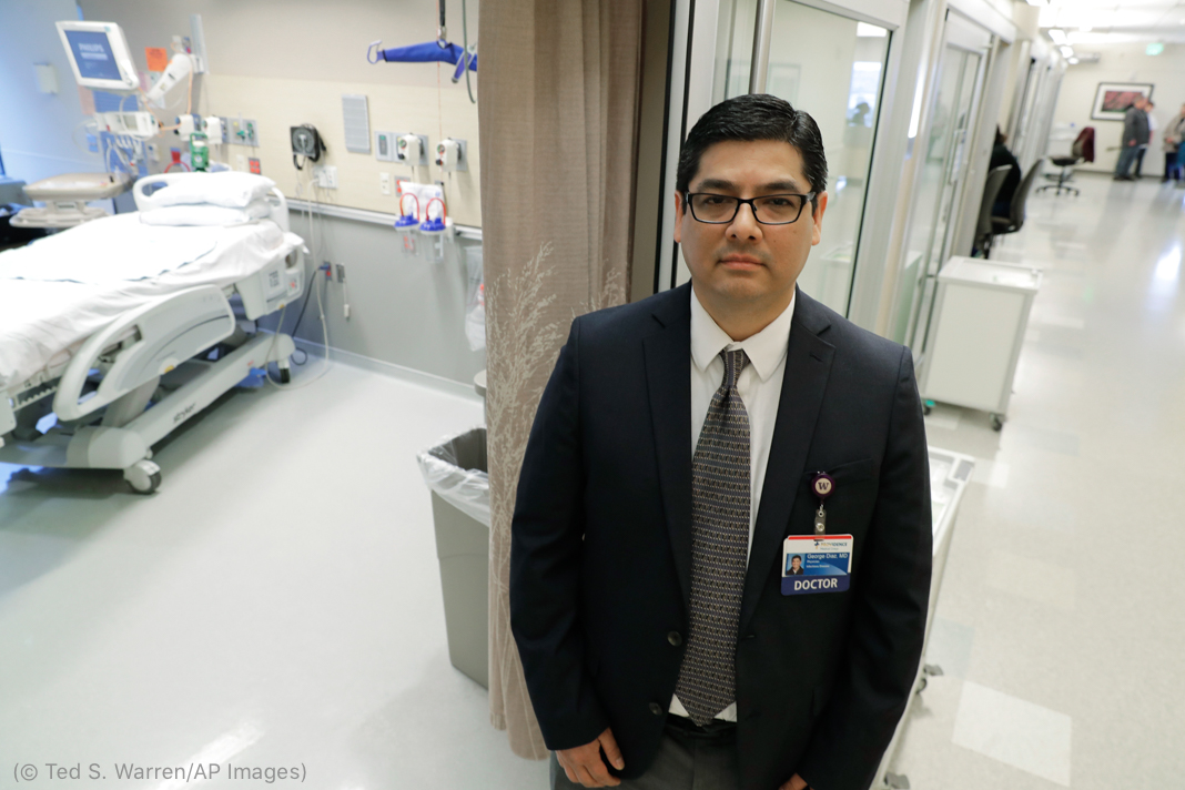 Man in suit standing in hospital hallway (© Ted S. Warren/AP Images)