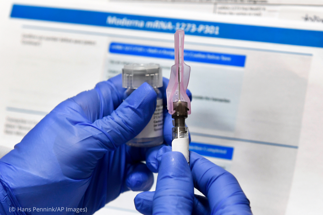 Gloved hands holding vial and hypodermic needle (© Hans Pennink/AP Images)