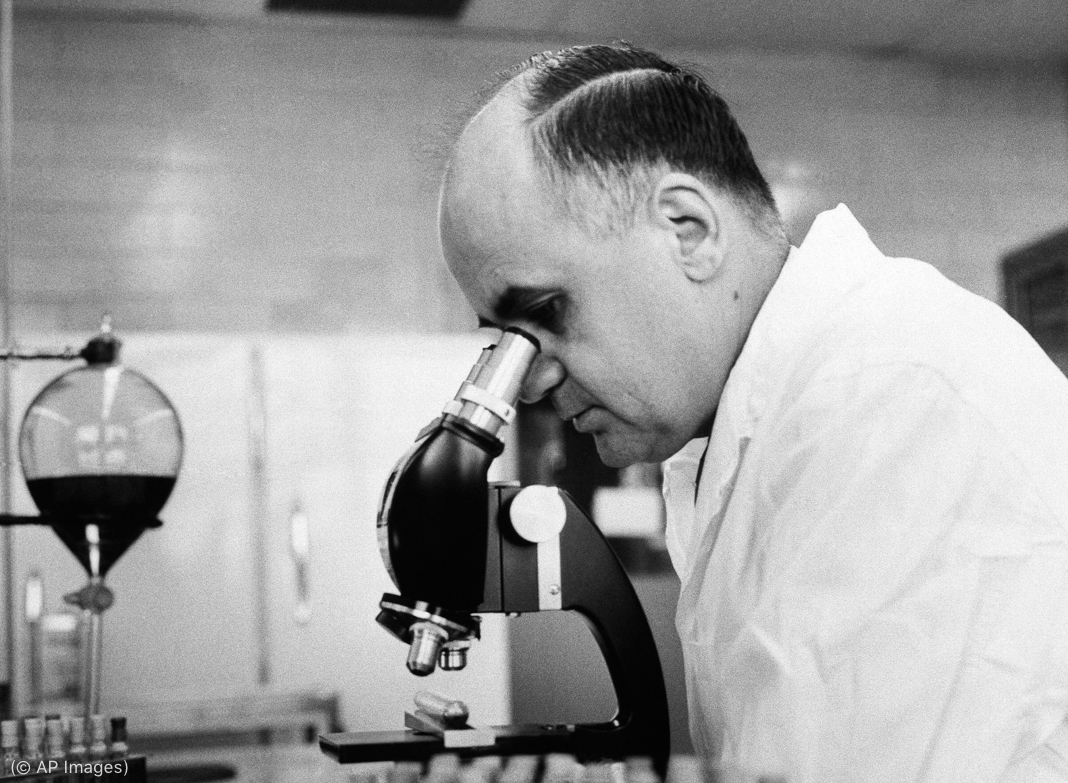 Scientist using microscope in laboratory (© AP Images)