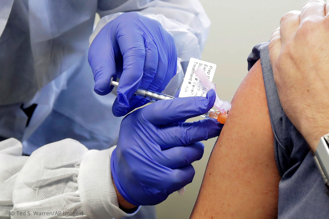 Gloved hand giving an injection (© Ted S. Warren/AP Images)