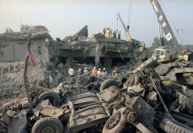 People wearing Red Cross emblems and cranes near rubble at blast site (© Jim Bourdier/AP Images)