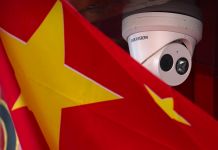 Chinese flag hanging near security camera mounted on ceiling (© Mark Schiefelbein/AP Images)