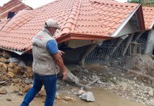 Man walking past destroyed home (USAID)
