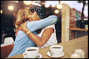 Photo of a smiling young woman hugging her friend