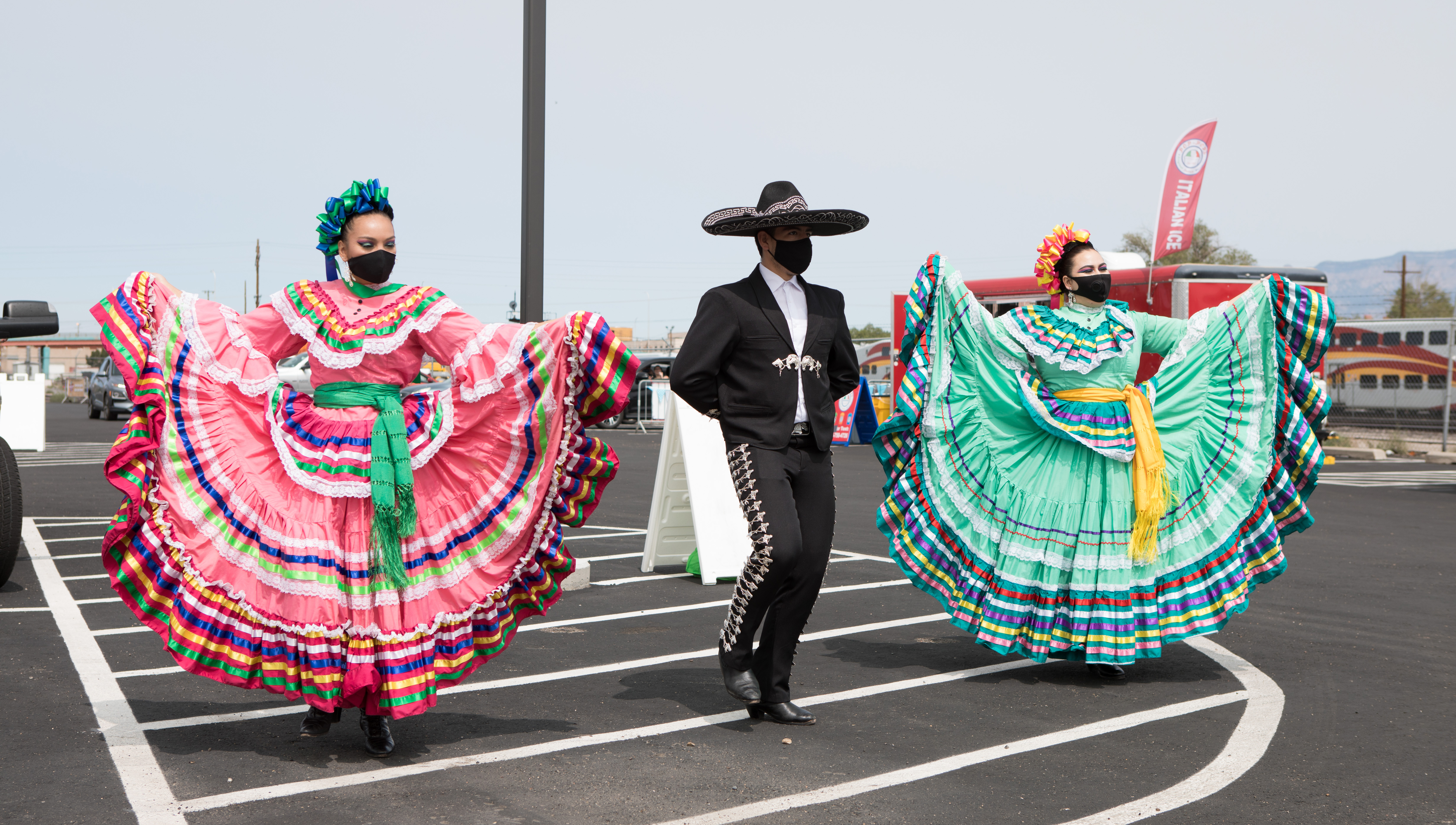 Mariachi dancers performing in a parking lot.