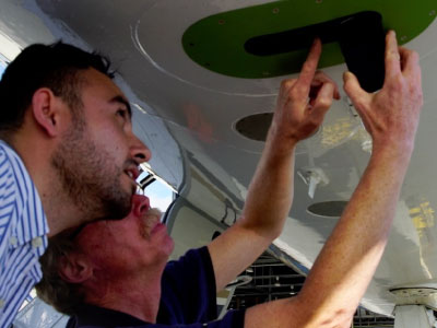 CORAL team members examine PRISM, an airborne instrument that measures the spectra of light reflected from surfaces below a plane. Credit: NASA