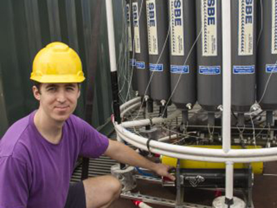 Noah Walcutt examines a holographic camera installed on a rosette. The camera can capture 40,000 images in a single deployment. Credit: SOI