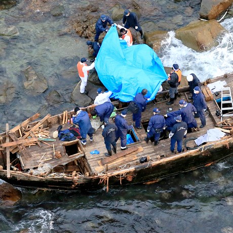 Police officers investigate a wooden boat marked with Hangul characters on Sado island, Niigata prefecture