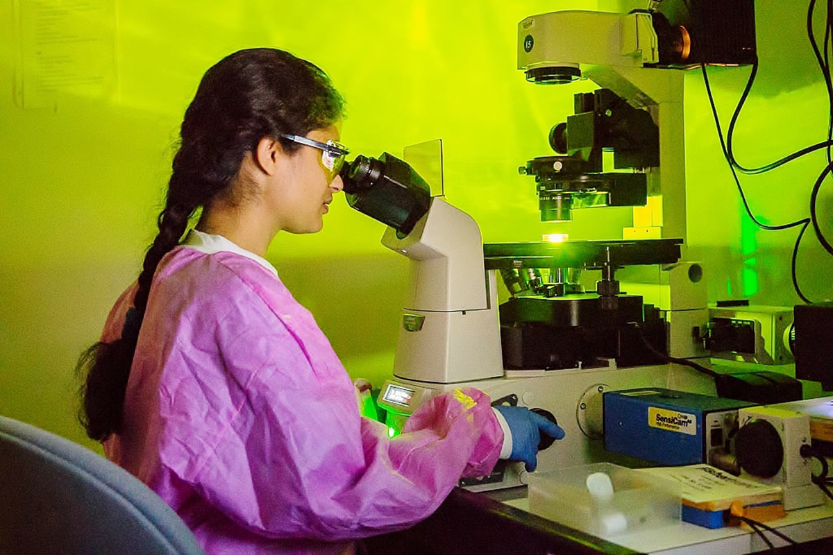 Women sitting down lookin through an microscope