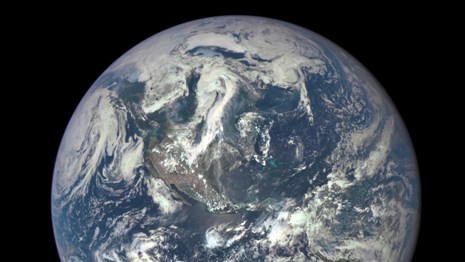 Blue Earth from space with clouds swirling over the western hemisphere. 