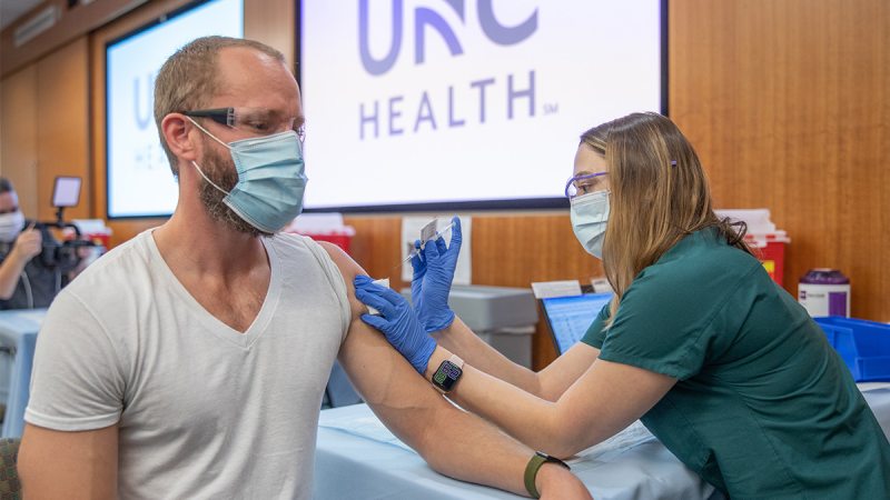 Autumn Petersen administers a COVID-19 vaccine to Brian Murray.