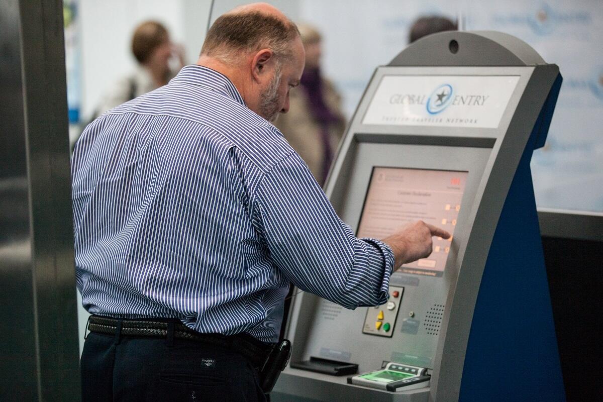 An arriving passenger at Newark [N.J.] Liberty International Airport uses a Global Entry kiosk to enter the U.S.<em> (photo by Josh Denmark</em>)