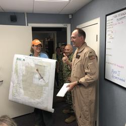 Woman holding map, standing next to man in military uniform