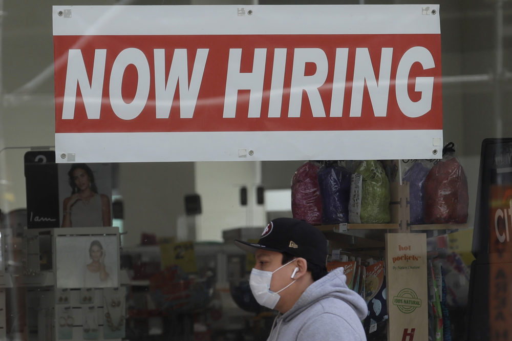 A man wearing a mask walks under a Now Hiring sign at a CVS Pharmacy during the coronavirus outbreak in San Francisco.  (Jeff Chiu/AP File)